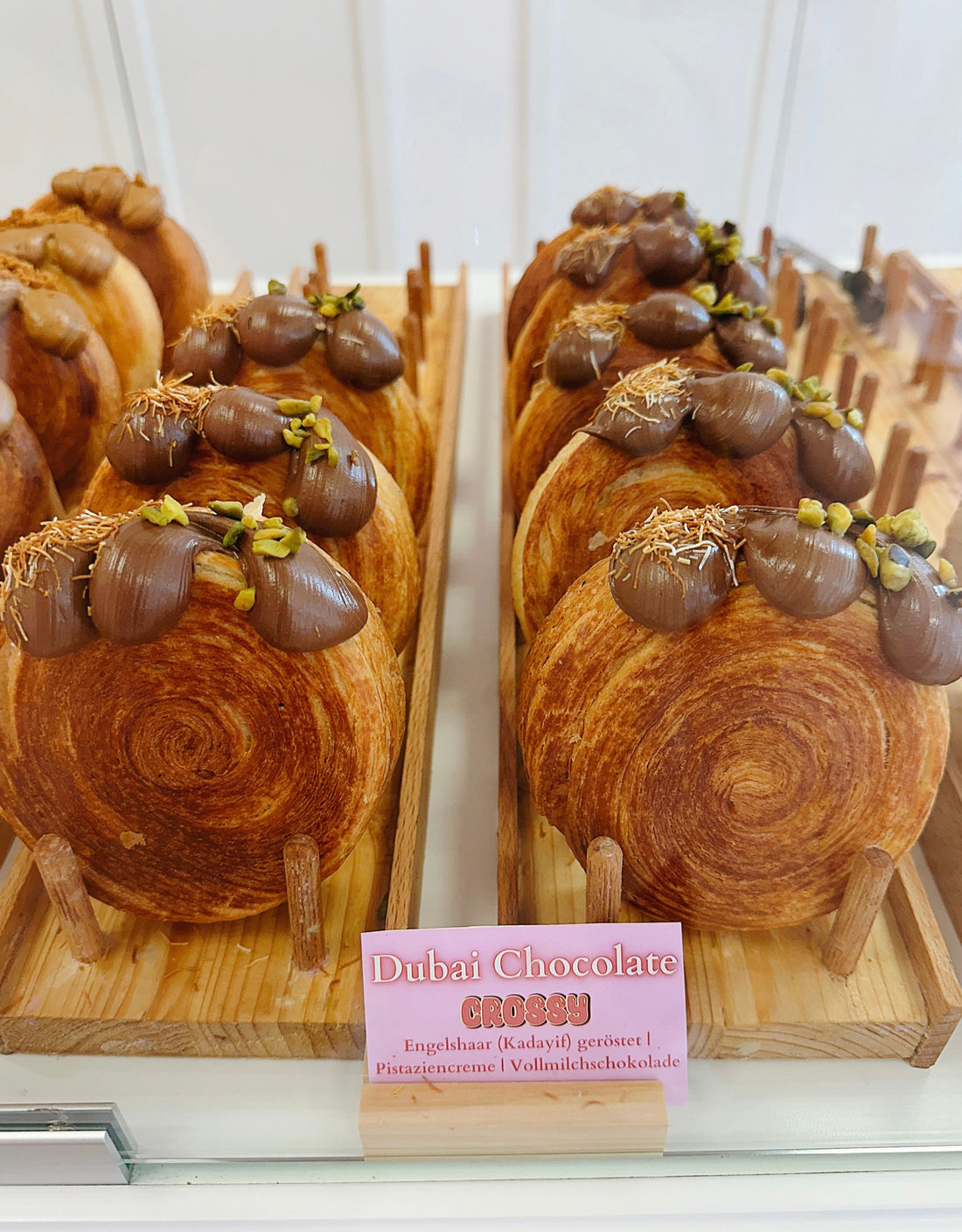 Dubai chocolate croissants topped with pistachios and chocolate on a bakery display