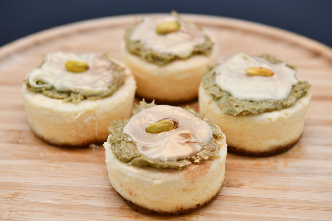 Mini cheesecakes topped with pistachio cream on a wooden board, styled like homemade Dubai chocolate desserts