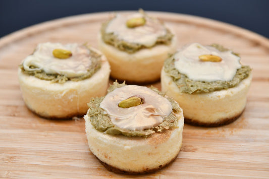 Mini cheesecakes topped with pistachio cream on a wooden board, styled like homemade Dubai chocolate desserts