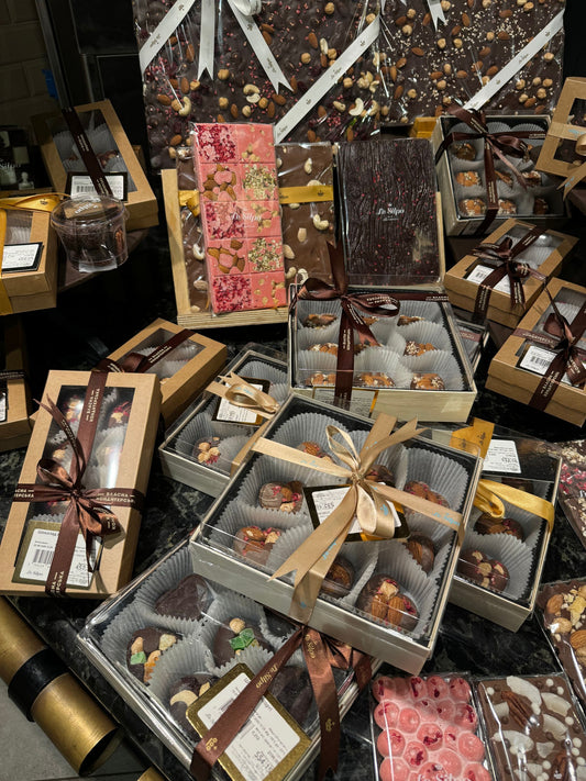A luxurious display of gourmet chocolate gift boxes with ribbons — corporate food gifts for 2026