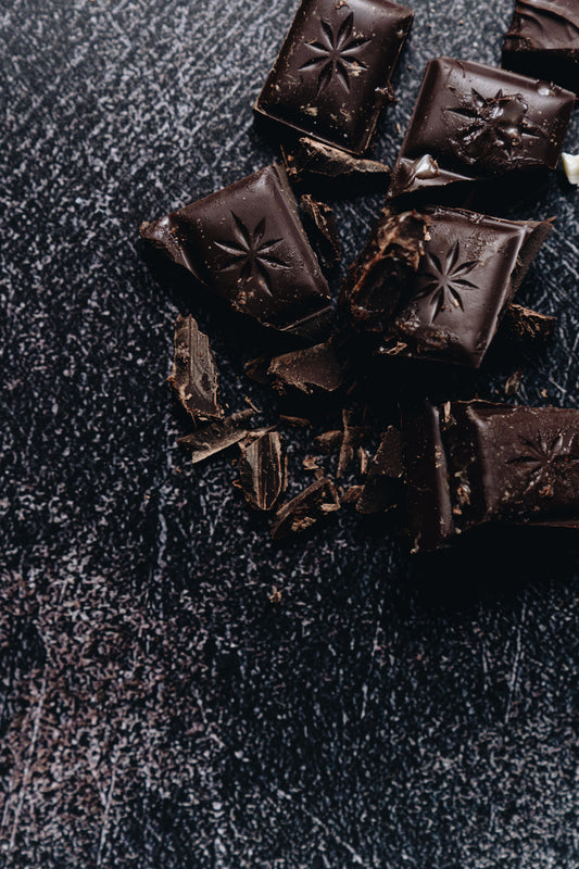 Dark chocolate shards and shavings on a moody textured surface — the base for gourmet Halloween chocolate treats
