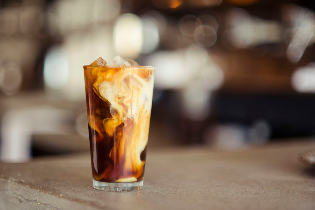 A pistachio iced latte in a tall glass on a tabletop, made at home