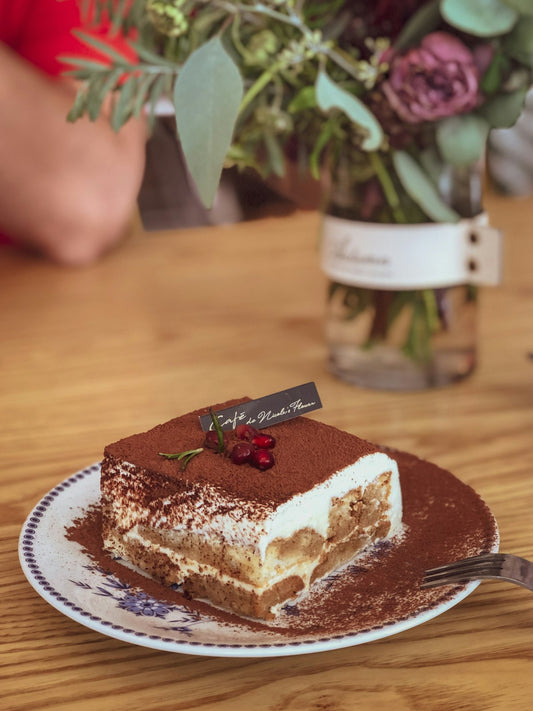 pistachio tiramisu dessert with cocoa dusting on a white ceramic plate
