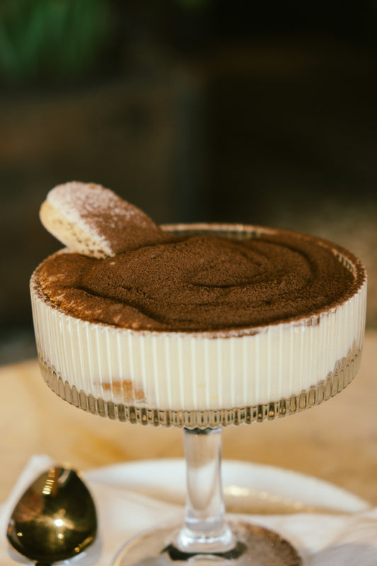 Creamy pistachio tiramisu dessert layered in a glass dish and topped with crushed pistachios